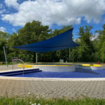 Manuell aufrollbares Sonnensegel blau über Pool